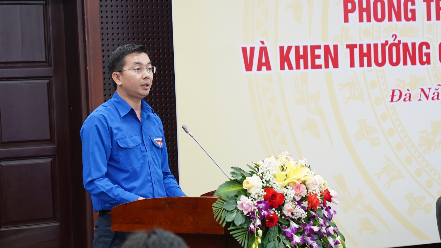 A person standing at a podium with a microphone and flowers

AI-generated content may be incorrect.